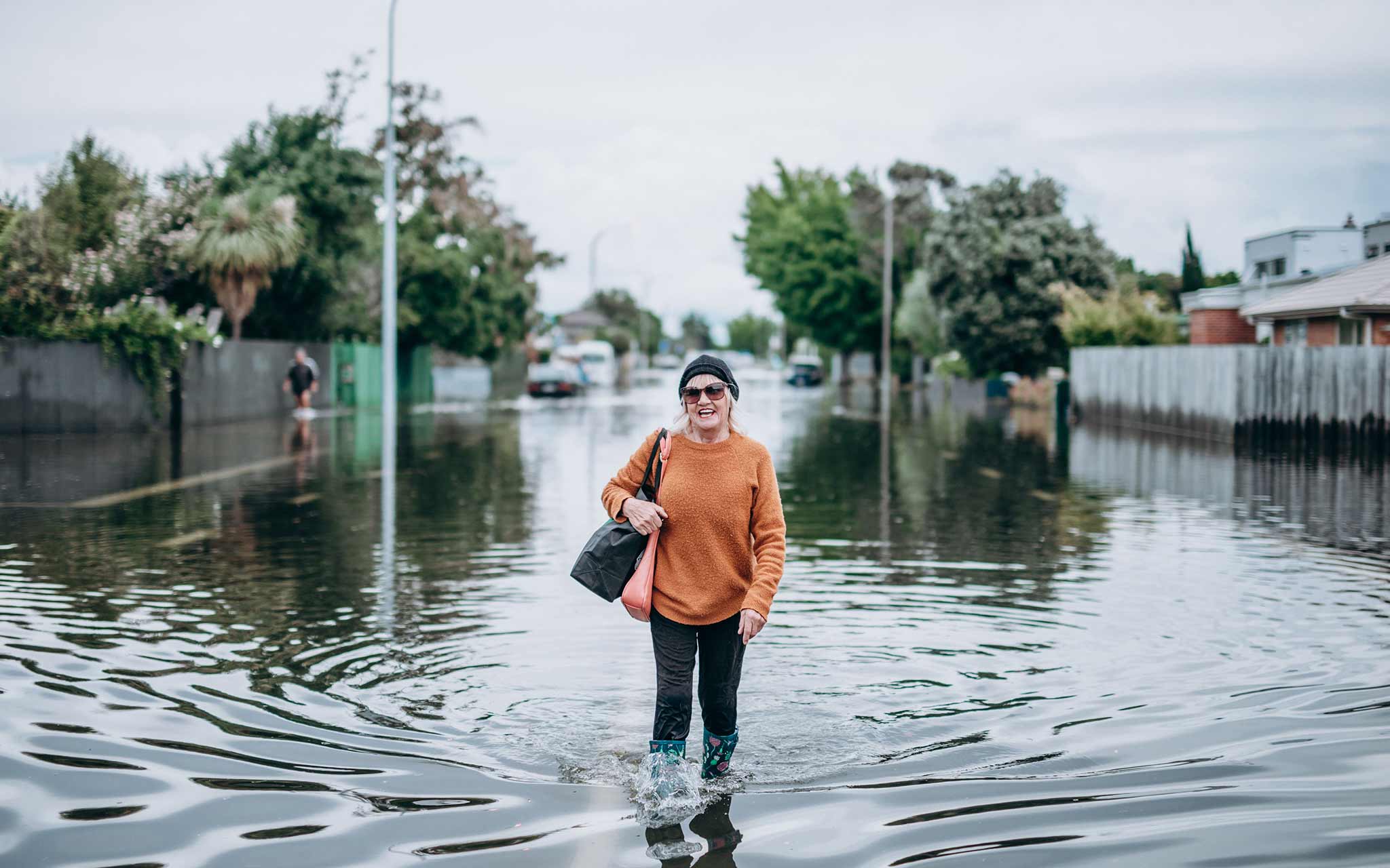 Photo of a woman standing in the middle of the road, in water past her ankles.