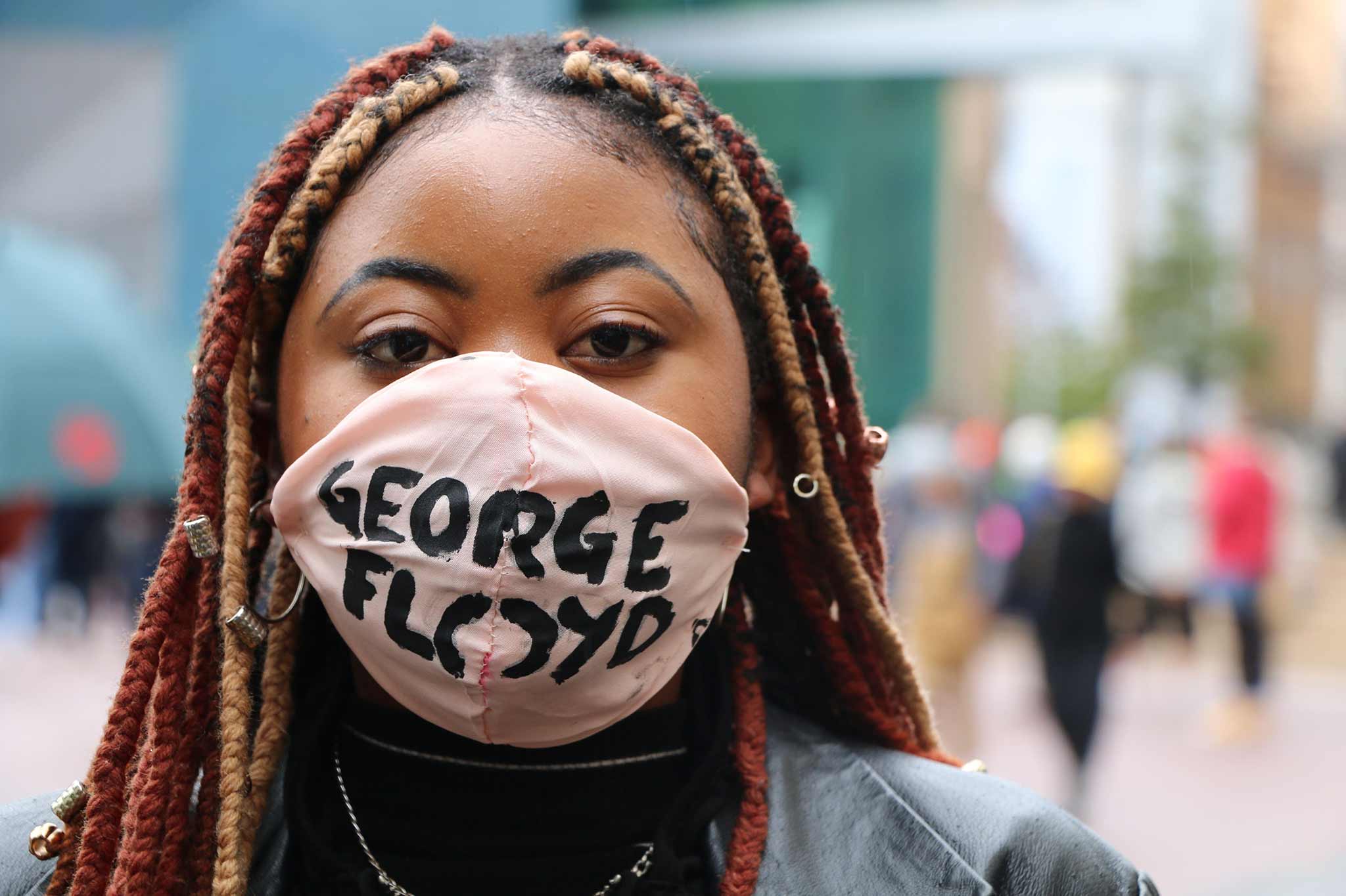 Photo of a woman looking at the camera, wearing a mask that says, "George Floyd".