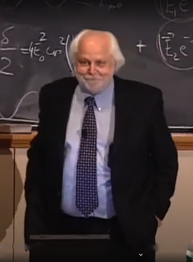 A. Neil Pappalardo lecturing in a classroom, standing in front of a chalkboard .