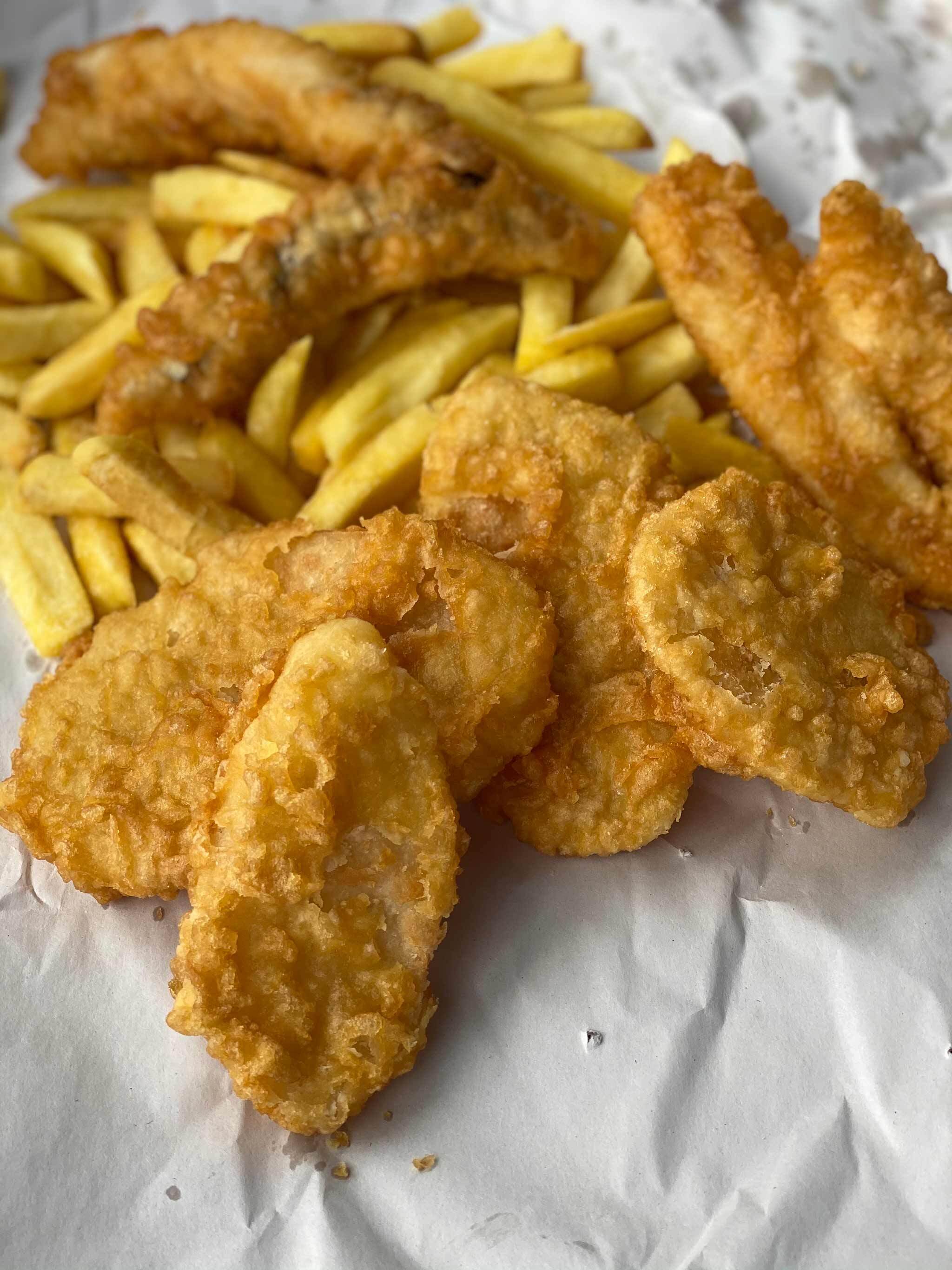 Photo of potato fritters, fish and chips on paper