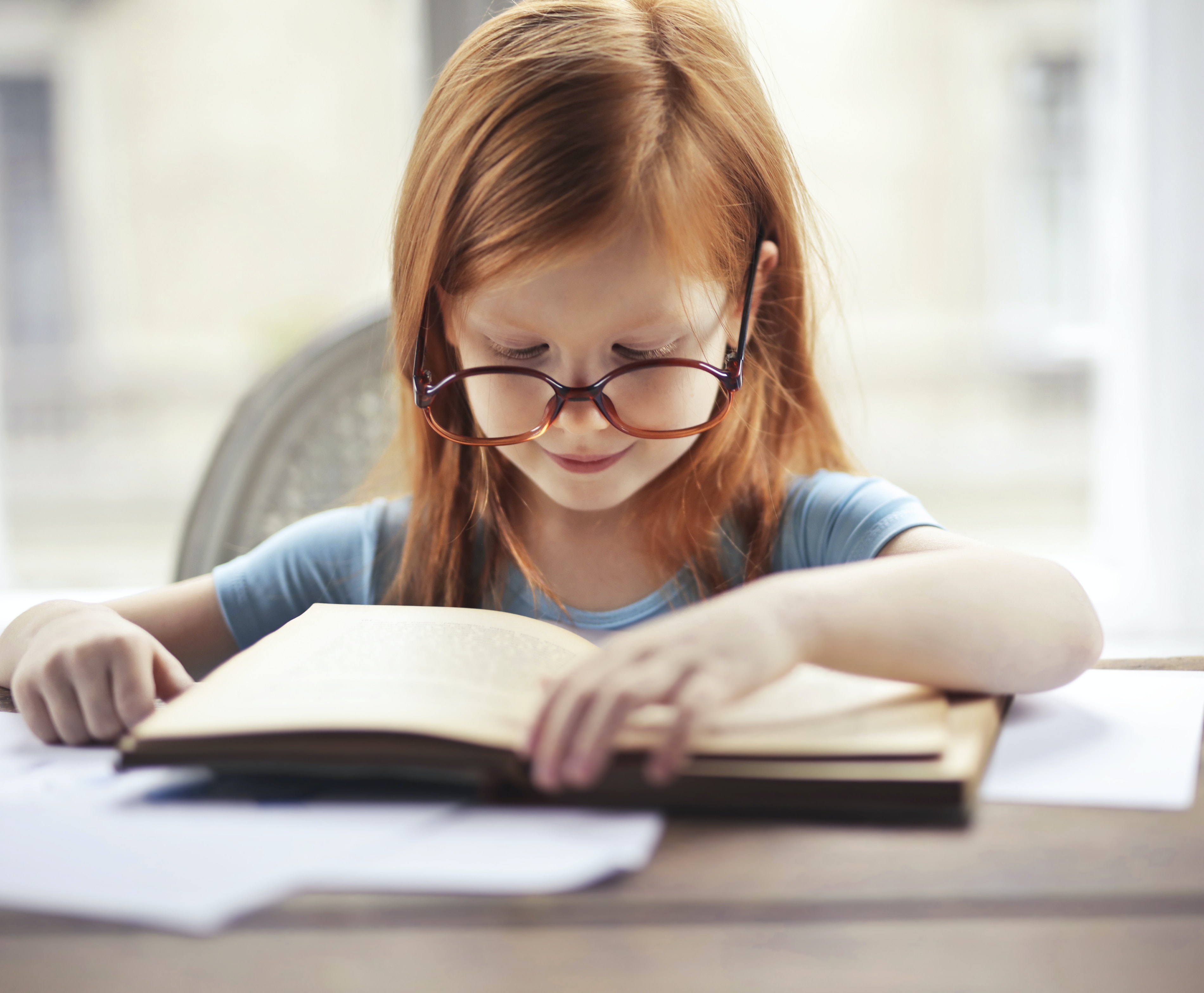 Dziewczynka w okularach czyta książkę