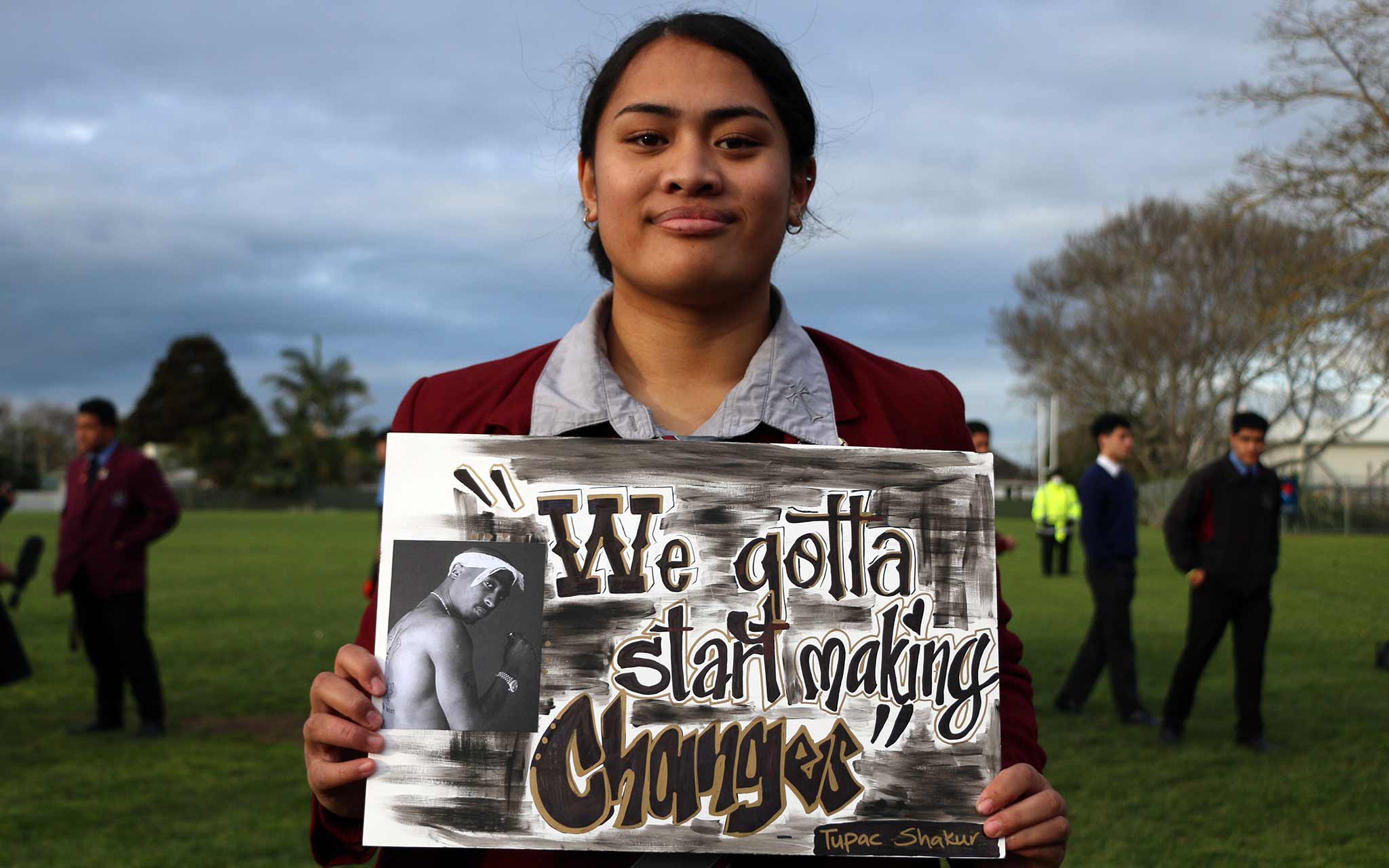 Photo of a girl holding a sign that says, "We gotta start making changes".