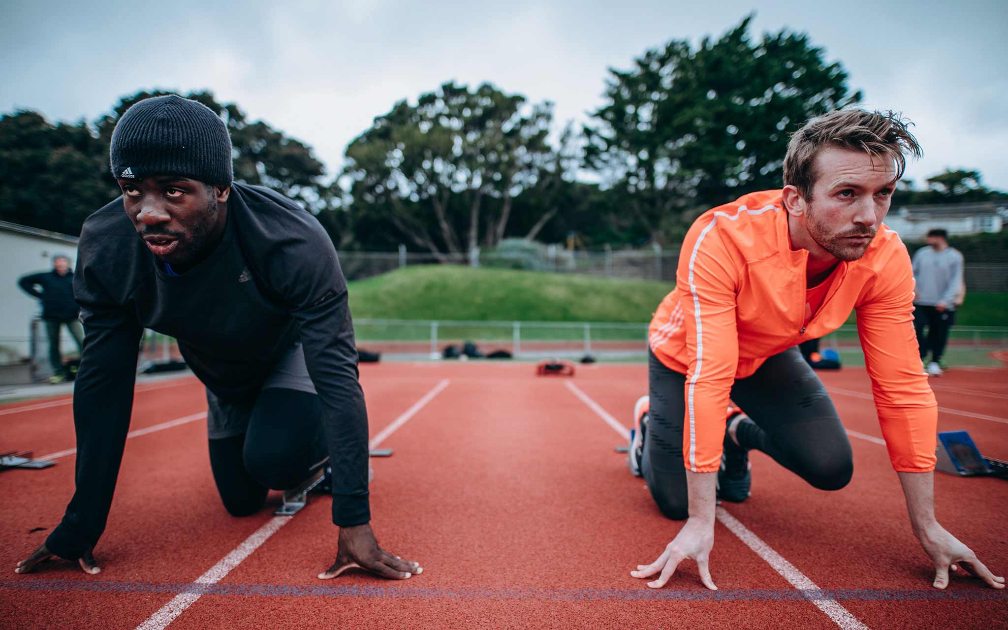 Photo of two men on a track getting ready to sprint.