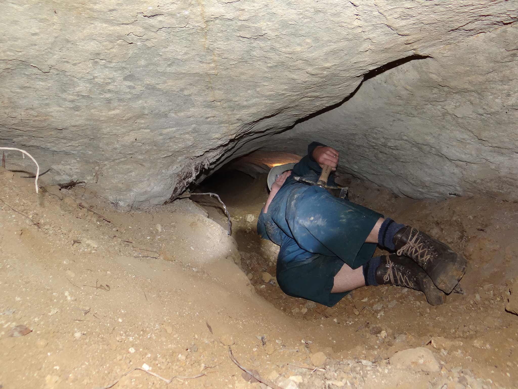 Man lying in narrow cave tunnel