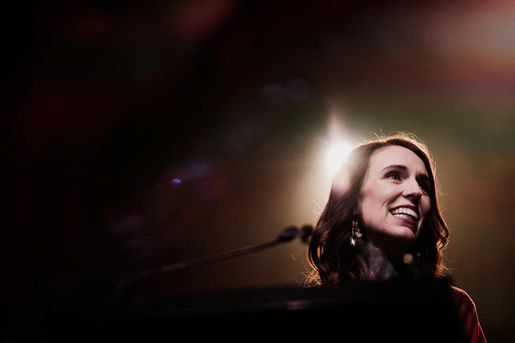 Photo of Jacinda Ardern smiling in the foreground with a light behind her.