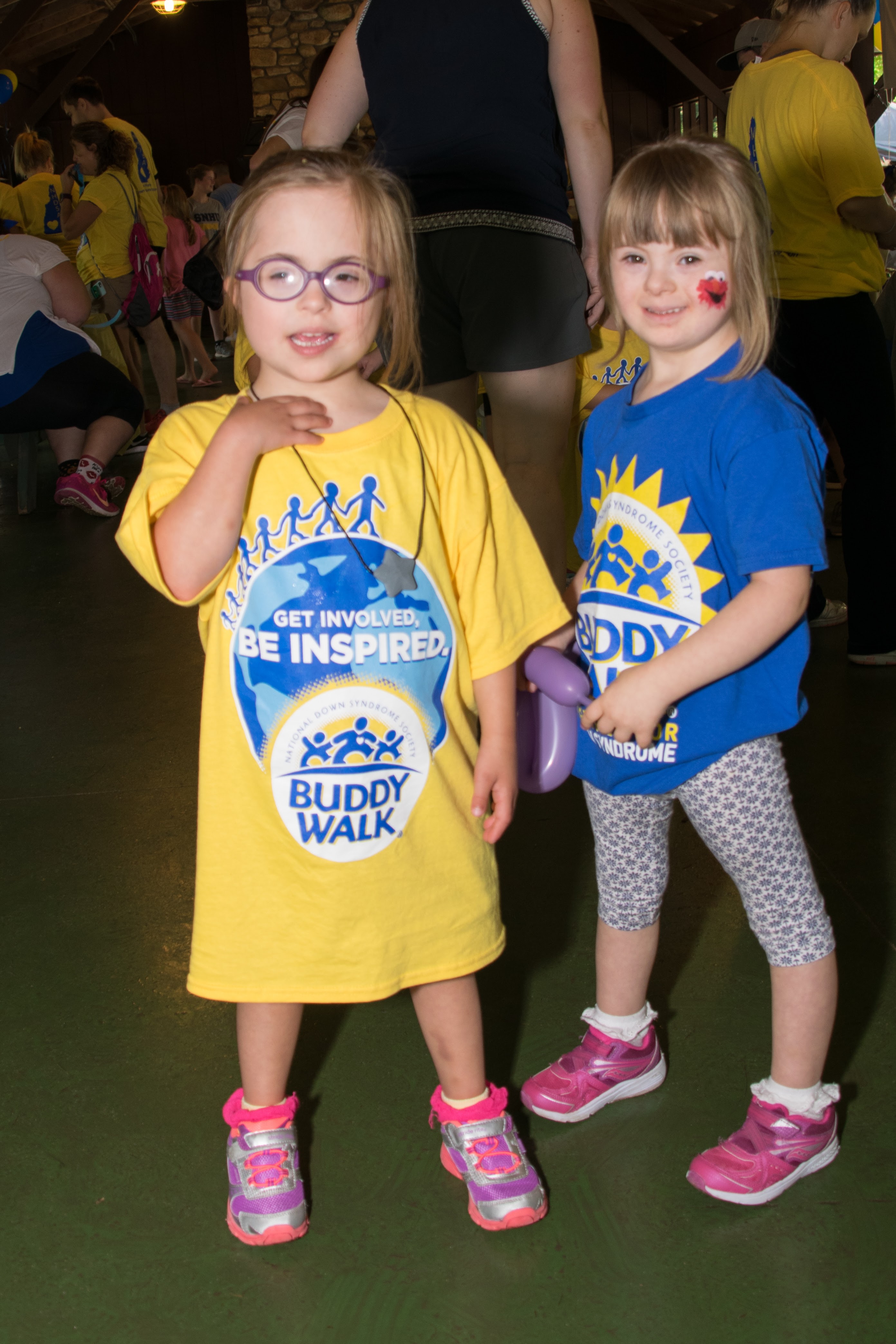 two small girls with down syndrome smiling at a buddy walk wearing their buddy walk t-shirts