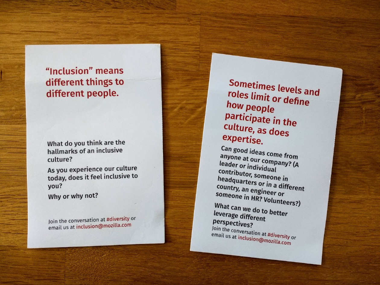 two slides of paper on a wooden surface telling about inclusion at mozilla