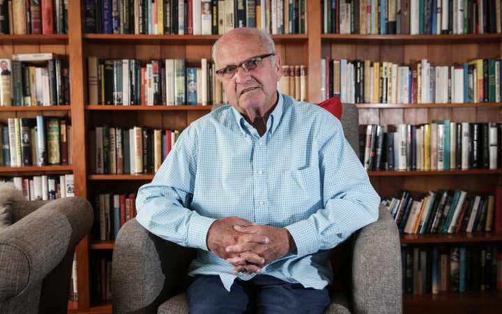 Mike Moore seated in front of bookshelves