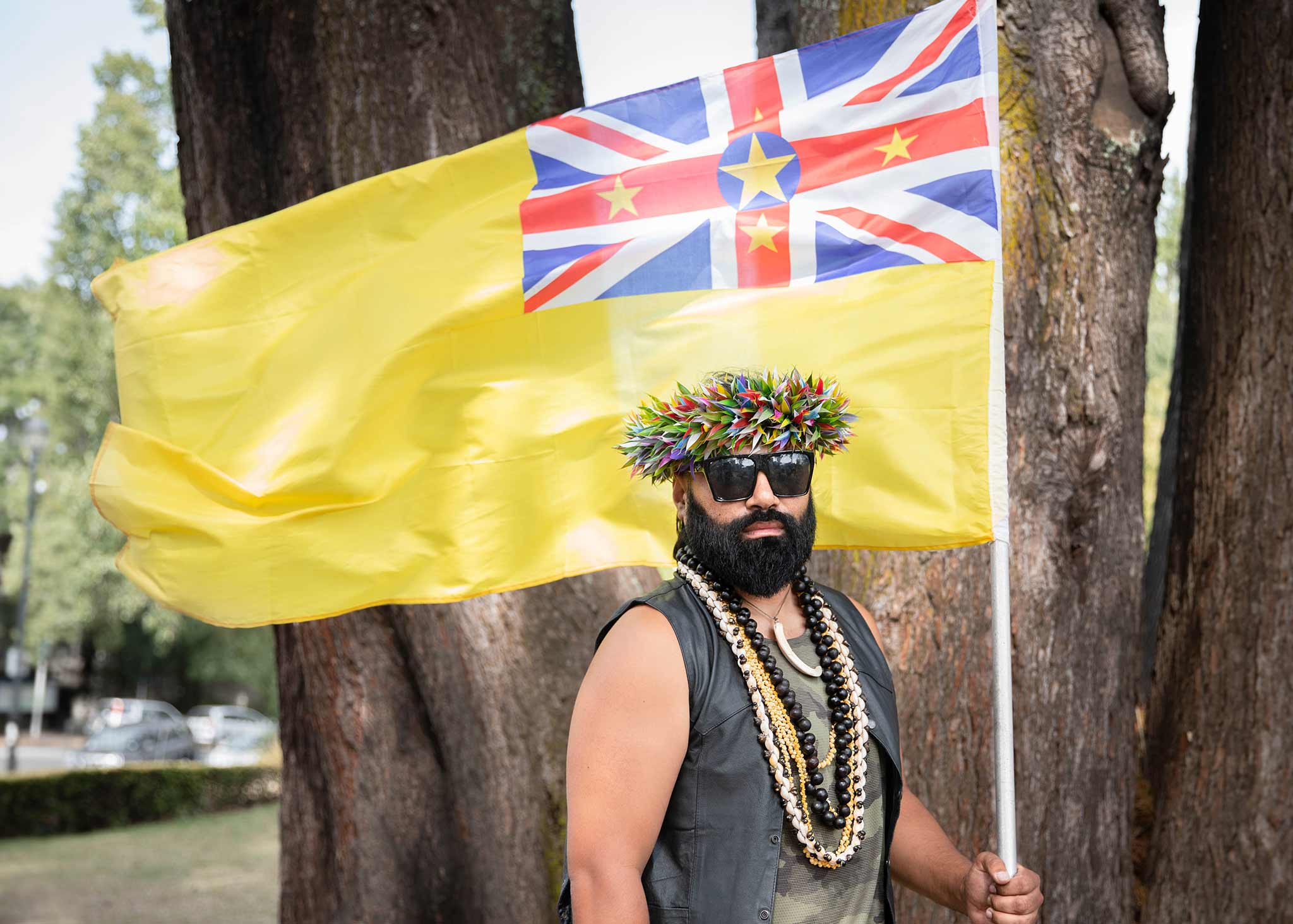 Photo of a man holding a flag in front of a tree.