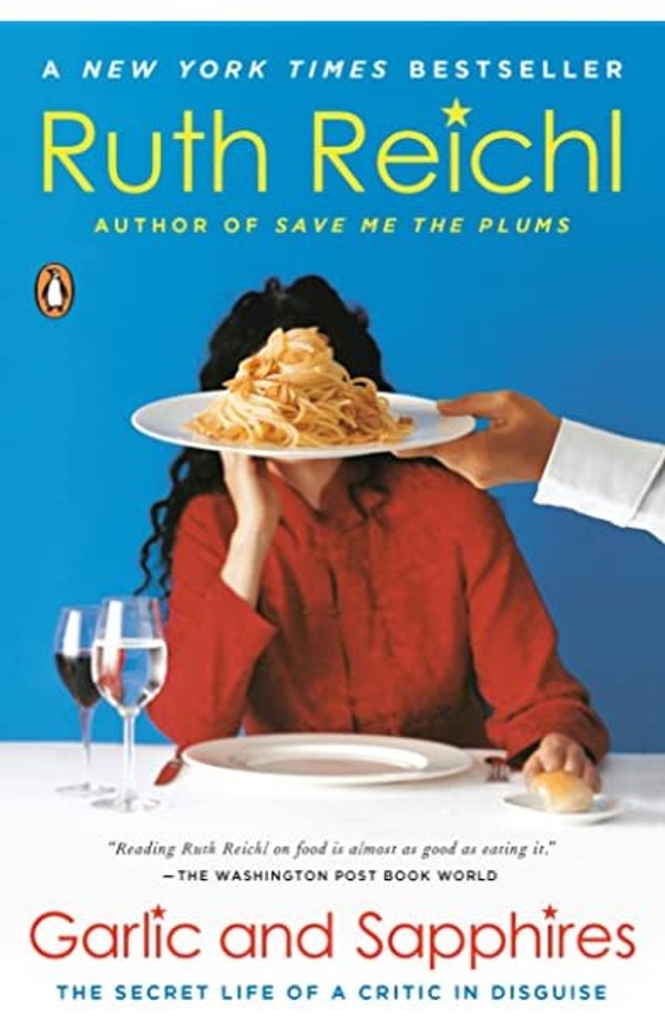 Book cover for Garlic and Sapphires: A woman sits at a table and a chef's hand holds out a plate of spaghetti, obscuring her face.
