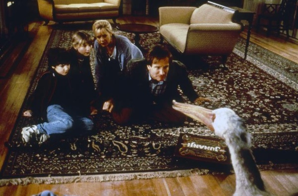 Screen grab of two children and two adults sitting on a rug with a menacing pelican advancing towards them